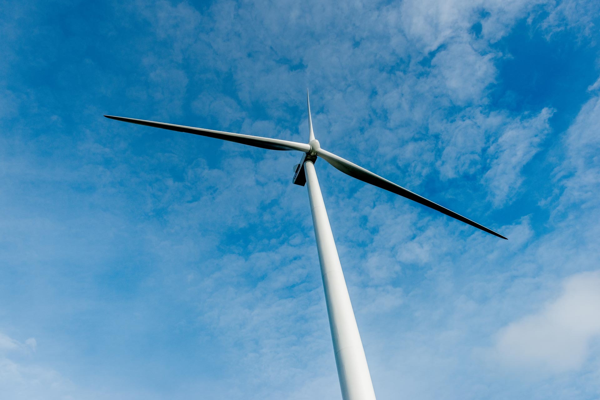 Vindmølle set i frøperspektiv, med en blå himmel i baggrunden