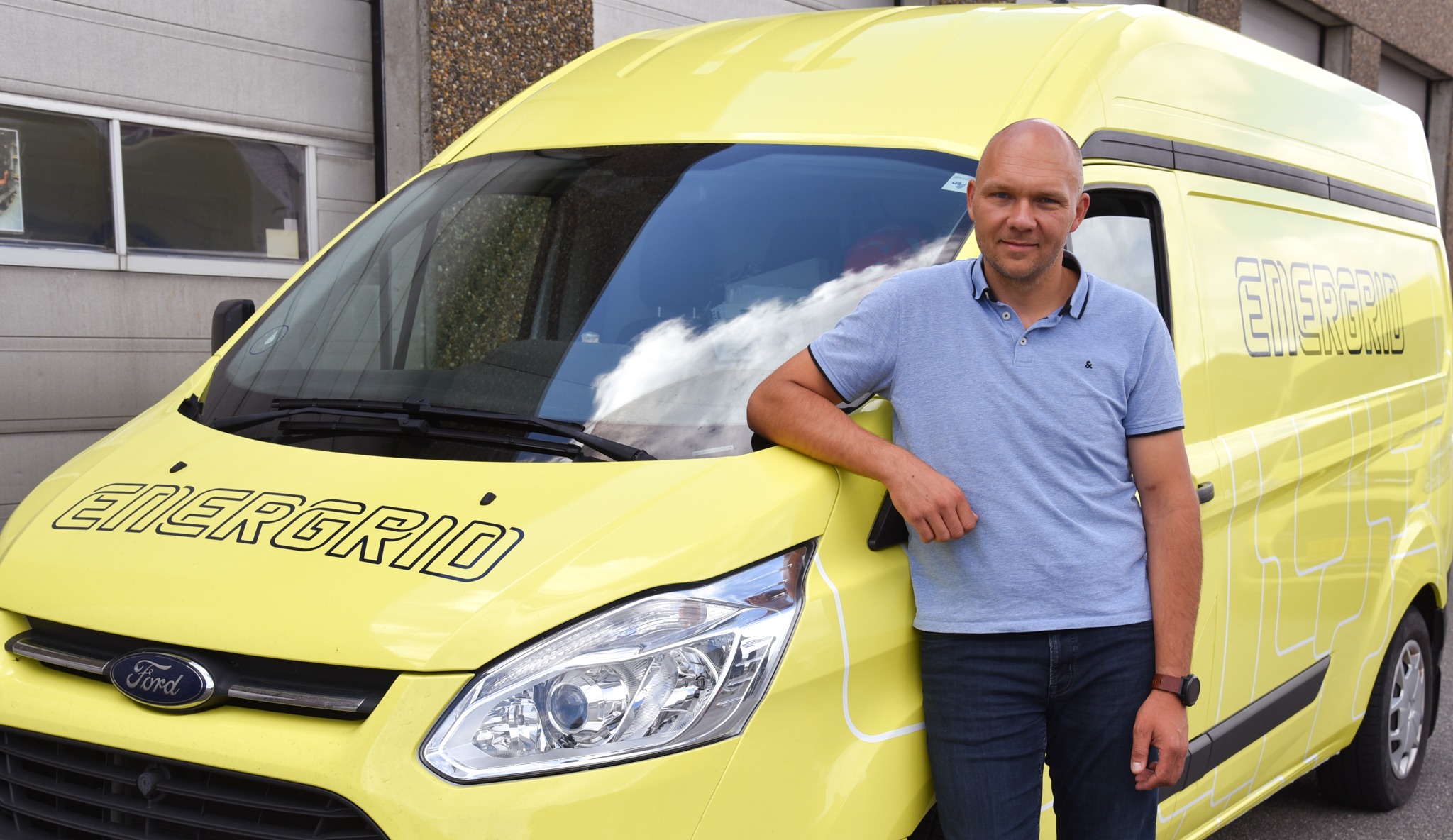 Energrid direktør med en gul energrid bil i baggrunden 